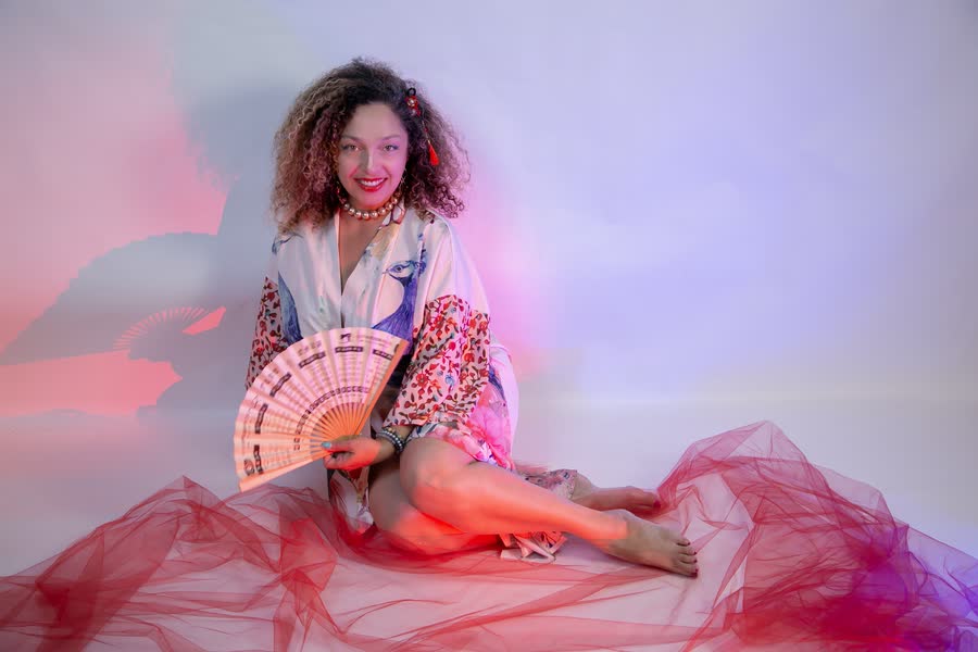 Woman in flowing red tulle with a decorative fan at a themed photo event