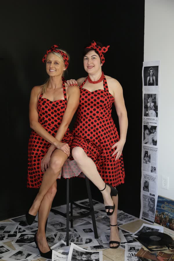 Two women in matching red polka-dot outfits at a retro themed photo event
