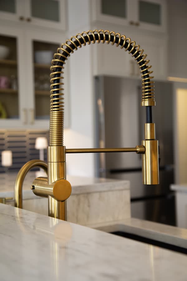 Brass spring-neck kitchen faucet detail against marble counter