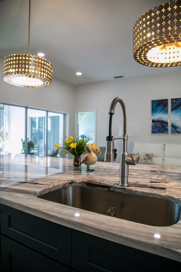 Brass faucet and undermount sink detail with chandelier behind