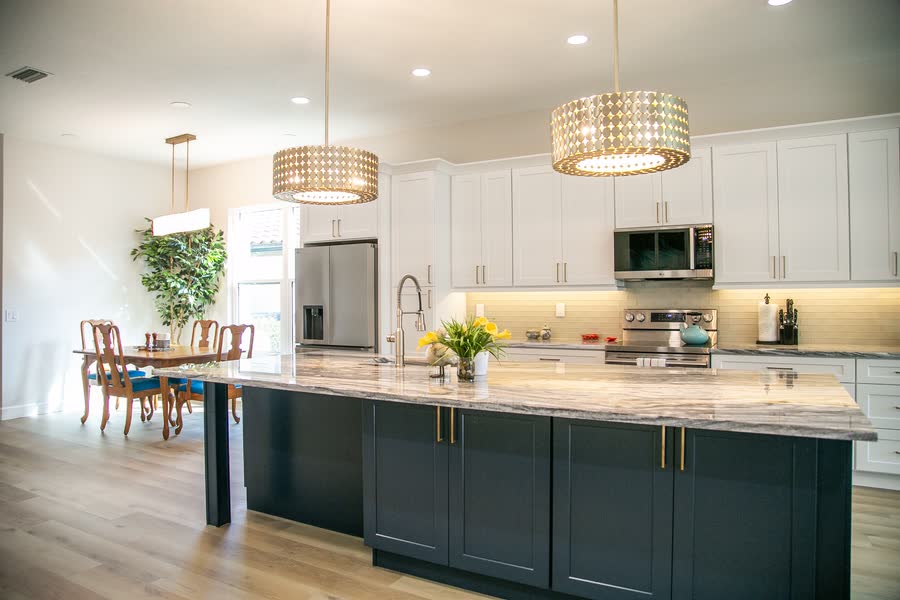 Navy island kitchen with brass fixtures and gold drum chandelier