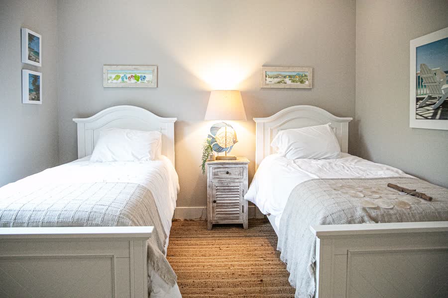 Coastal styled guest bedroom with twin beds and warm lamp light