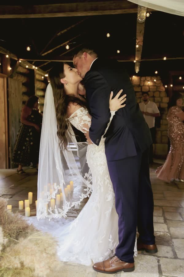 Bride and groom embracing by candlelight at a barn wedding ceremony