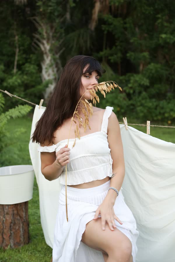 Outdoor portrait of a woman in white linen among greenery