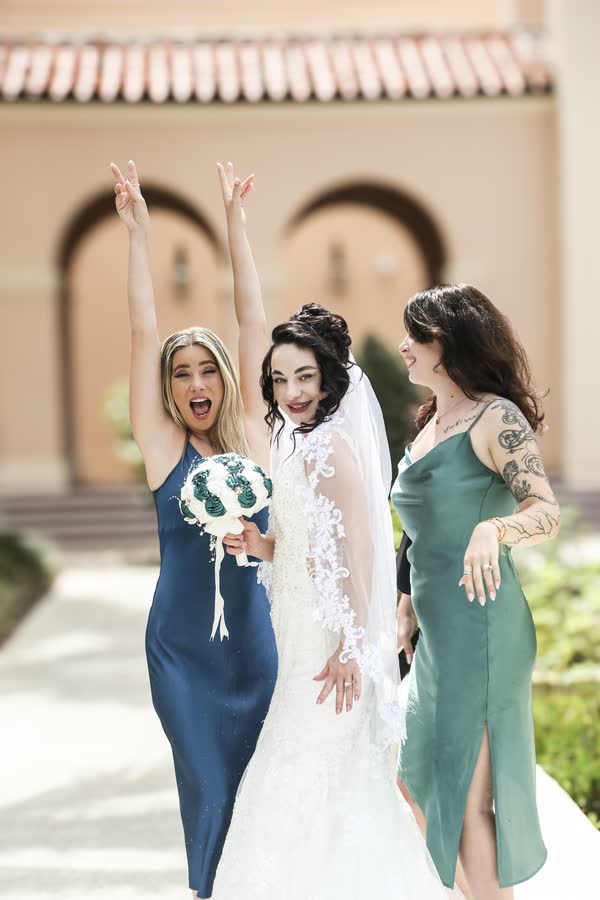 Bride with her wedding party beneath a floral arch